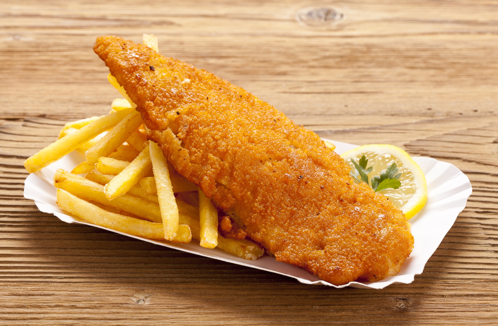 Fried fish and chips on a paper tray - Natural wooden background