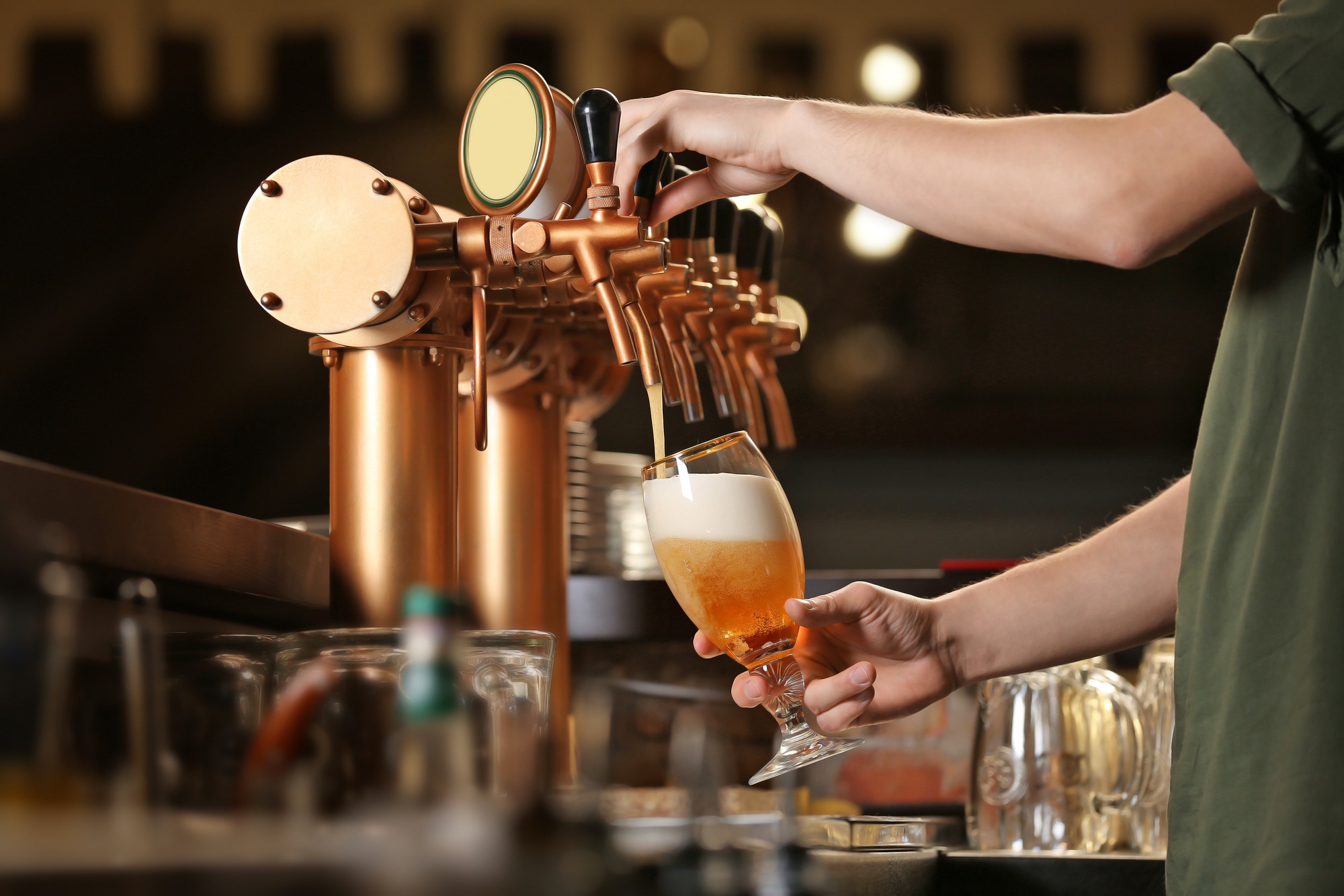 Barman hands pouring a lager beer in a glass.